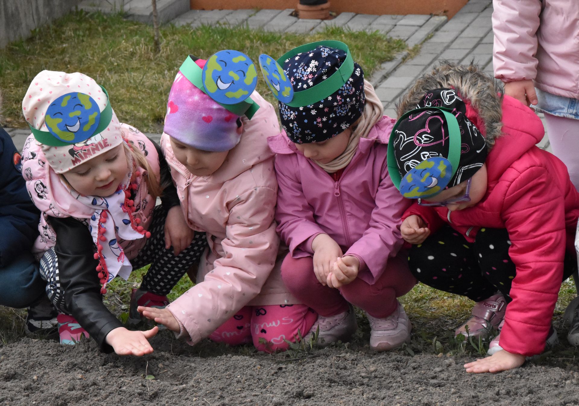Dzieci z Przedszkola nr 3 wysiewające łąkę kwietną w przedszkolnym ogródku